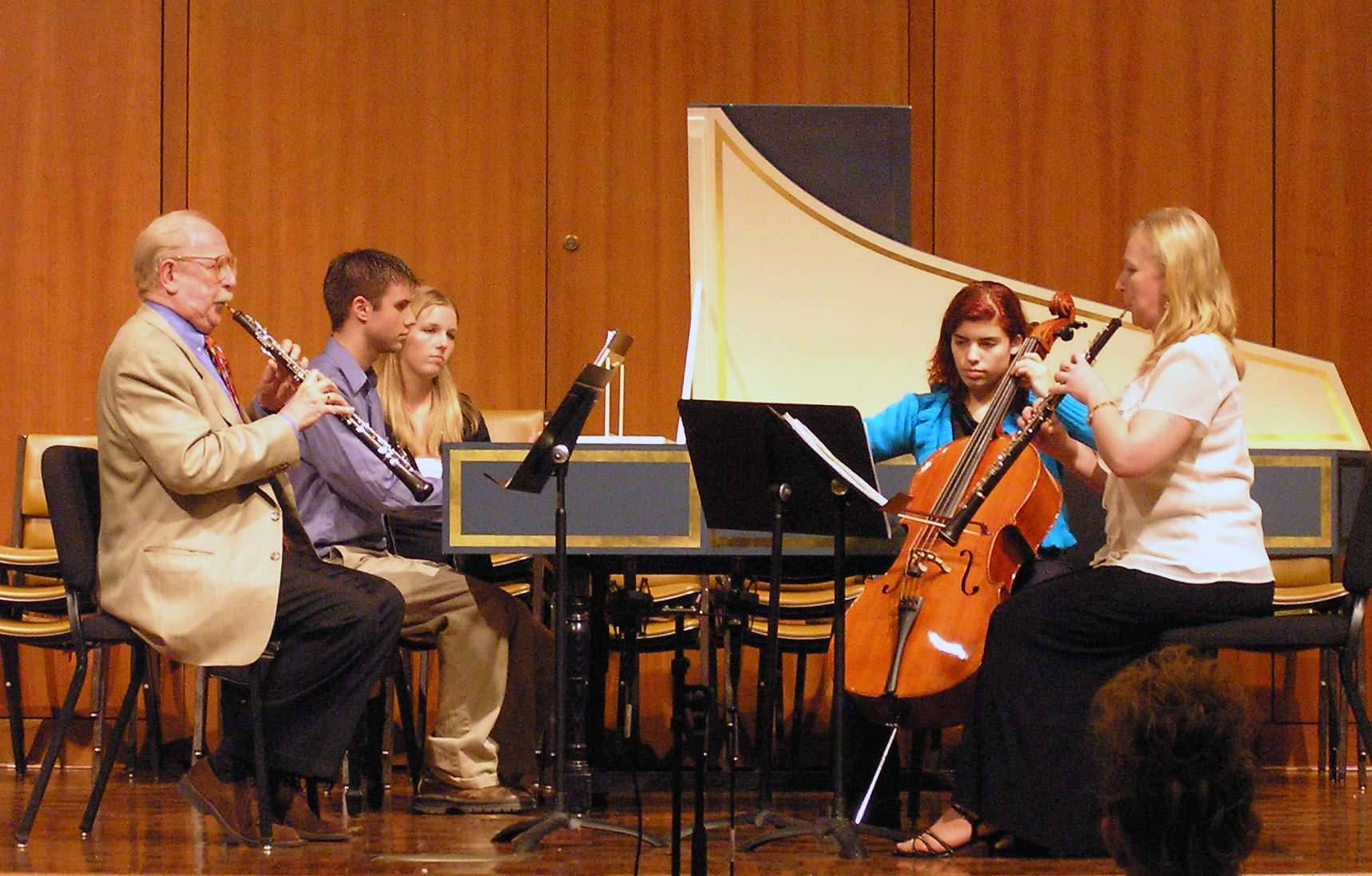 Musicians on the stage playing oboes, cello, and harpsichord.